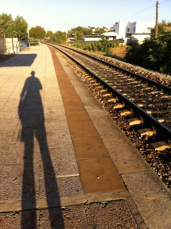 a person is casting a shadow on a train track