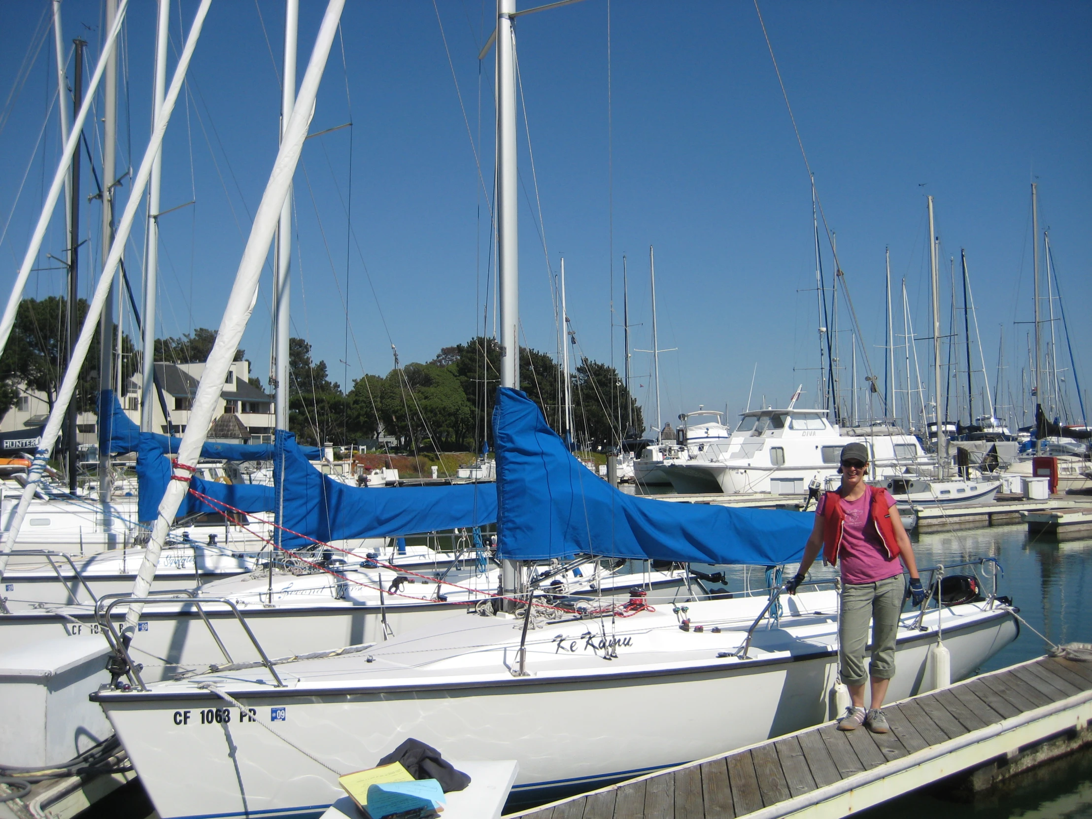 a woman standing on a dock near a number of sailboats