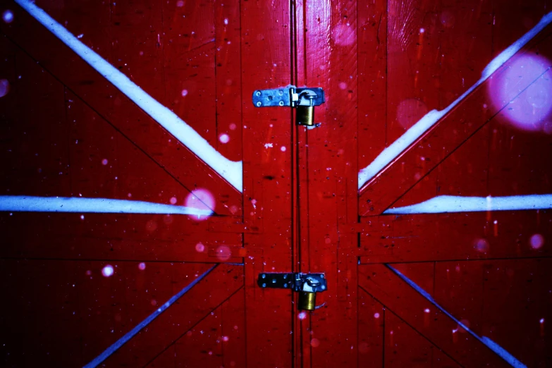 a red door with white painted beams and blue handles is in front of some red paint