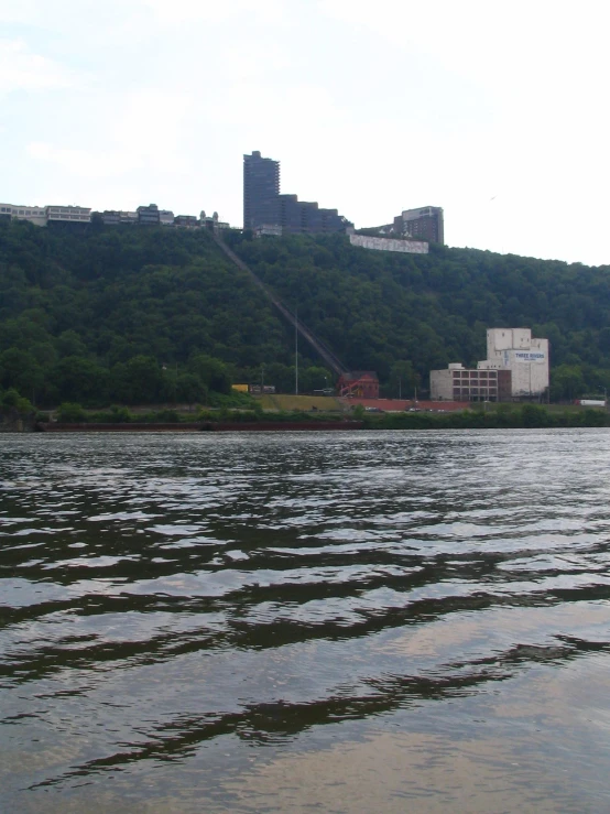 there is some water on the lake with buildings on the hillside behind it