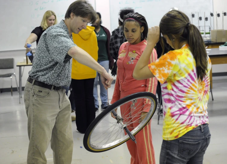 a man showing another woman how to hold her bicycle wheel