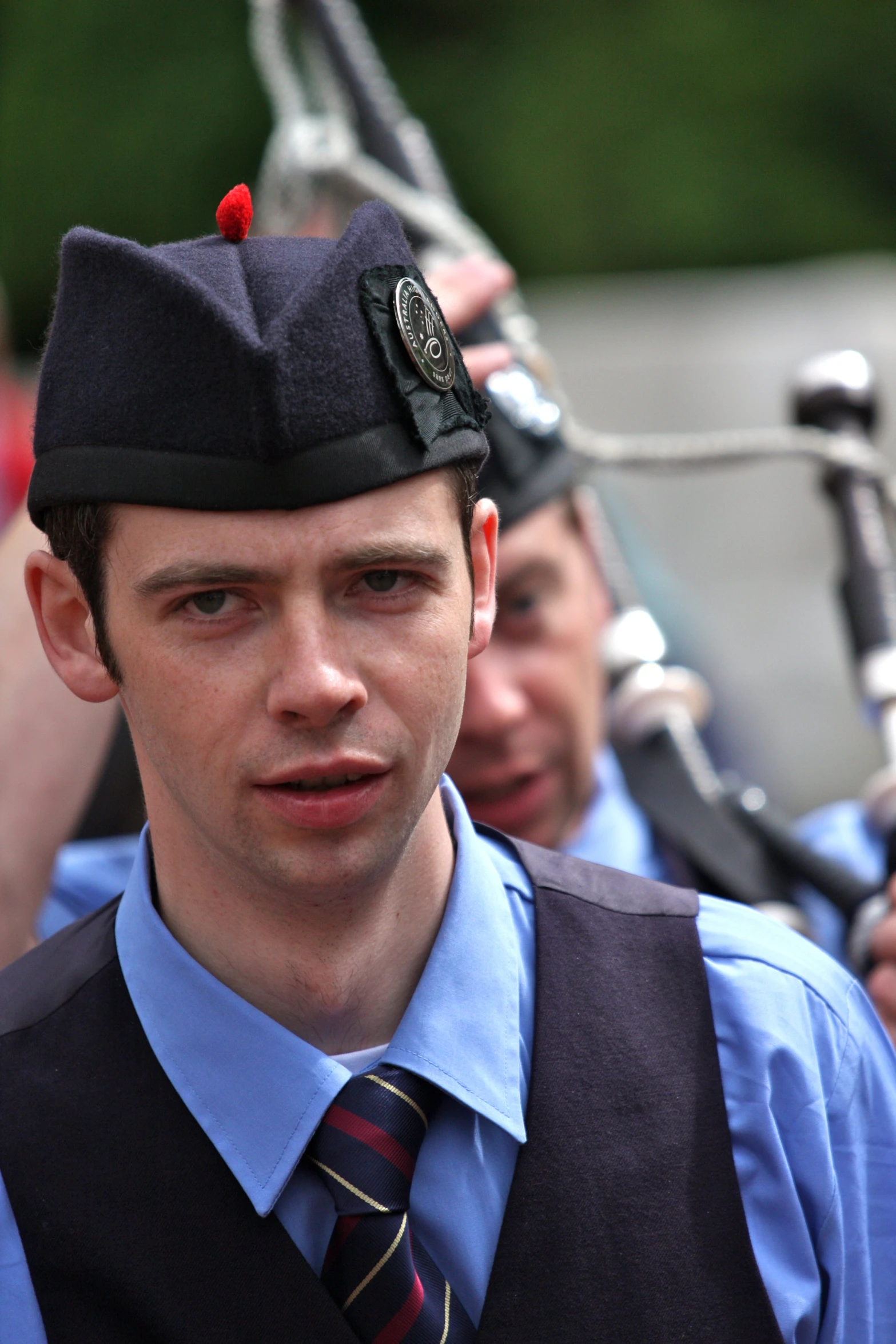 a young man dressed in an officer's uniform and standing next to other men with rifles