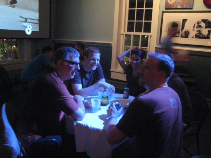 four men sitting at a table in a dimly lit restaurant