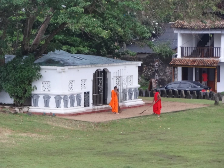 two monks walking toward an orange building in the middle of the day