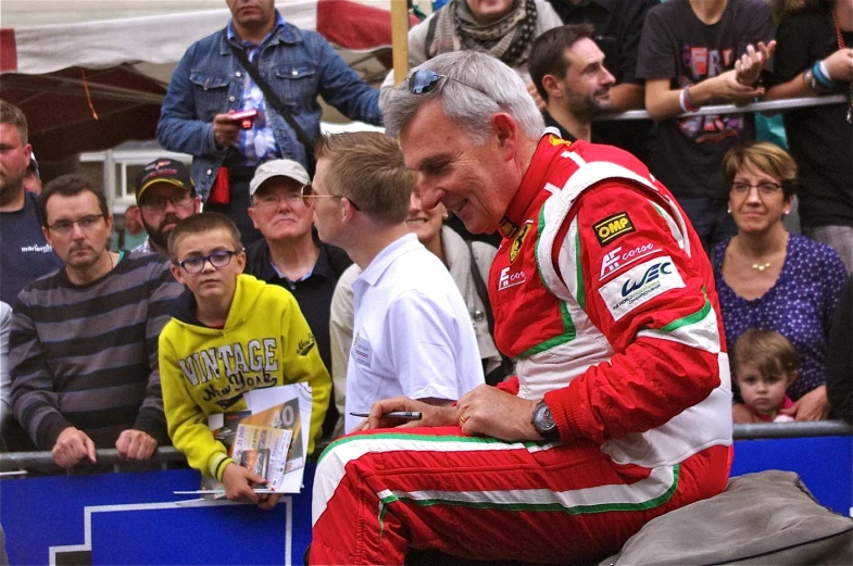 an older man sitting on the bench at a racing event