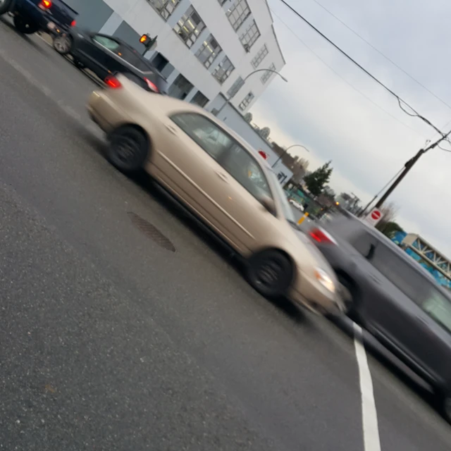 cars driving down the road in front of a building