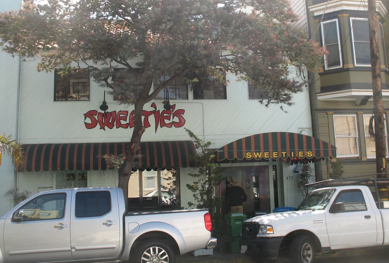 a white truck parked outside a storefront next to a tree