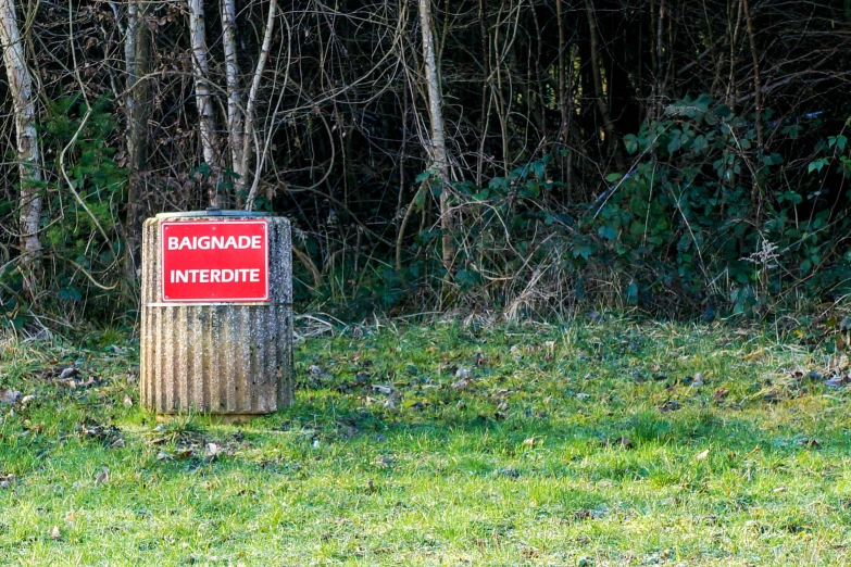 red sign that is sitting in the grass near trees