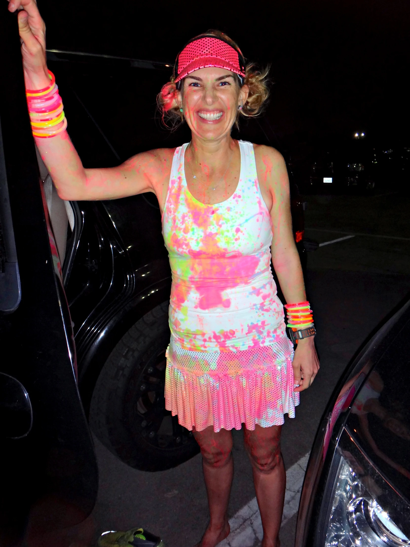 a woman in a pink dress and white top standing next to a car