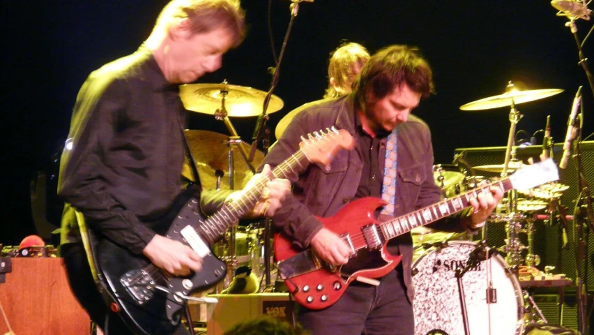 two people playing musical instruments on stage with other musicians