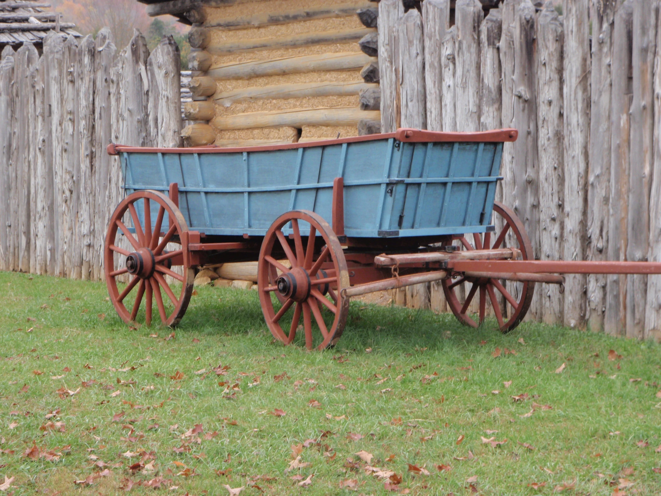 an old wooden wagon in front of a wooden fence