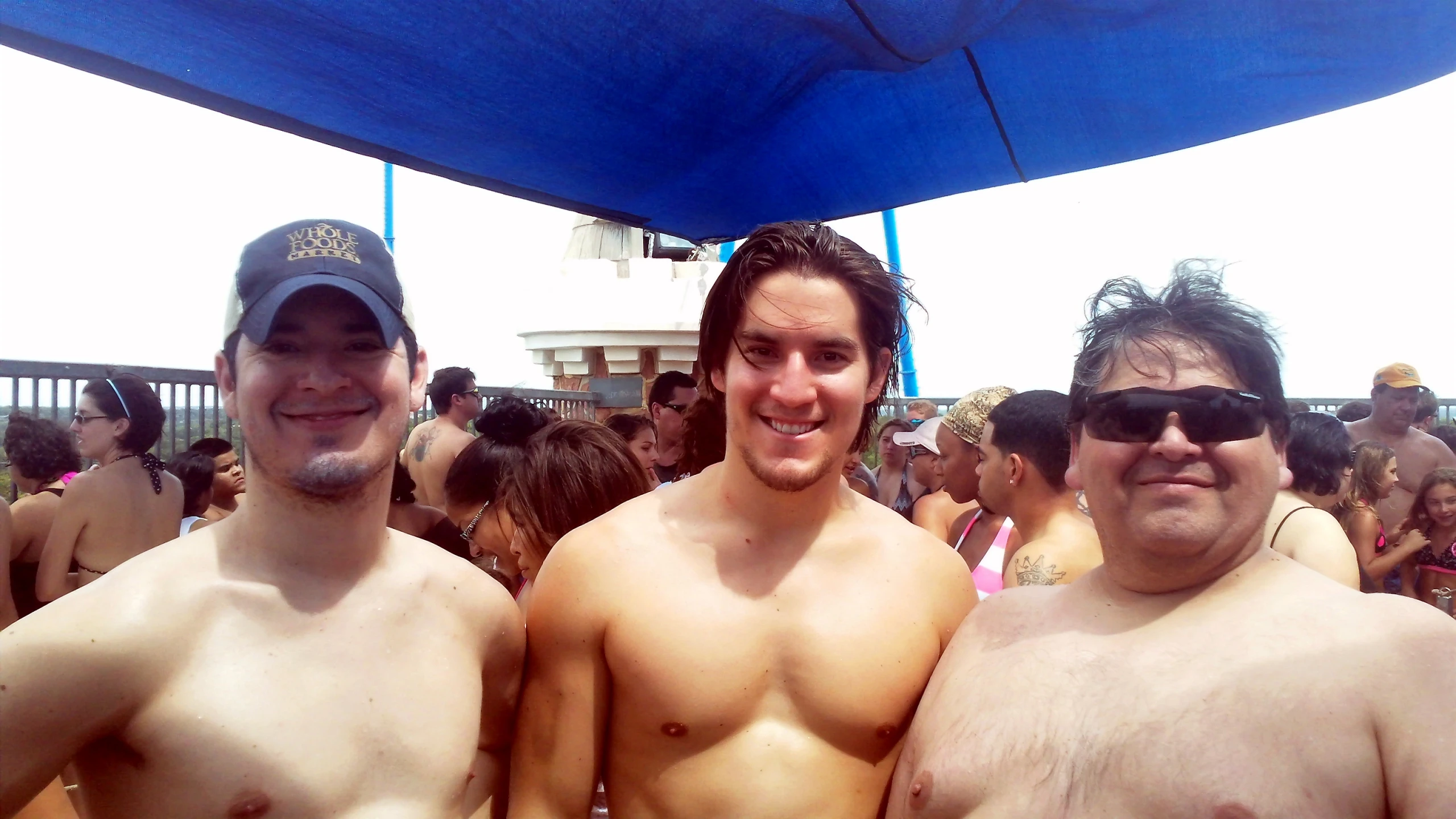 three shirtless men are in a crowd with sunglasses on