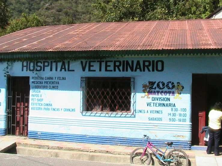 a couple walks past a building in front of a building that contains medical office, medical specialty stores and a bike