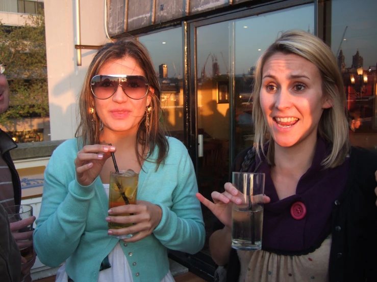 two women posing for a po while having drinks