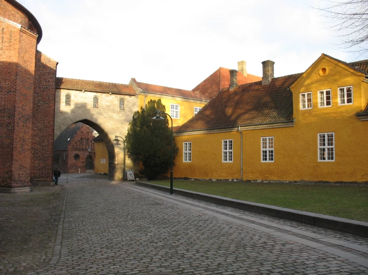 a narrow cobblestone street leading through two old buildings