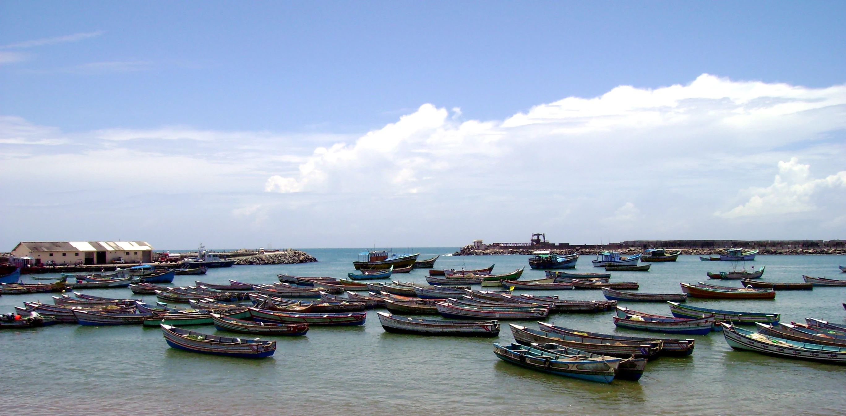 boats moored in the harbor under the cloudy blue sky