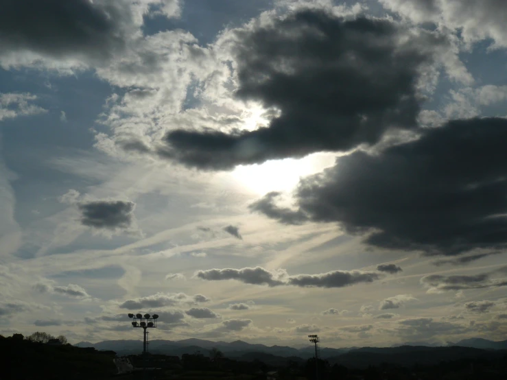 the sun is shining through some clouds above the field