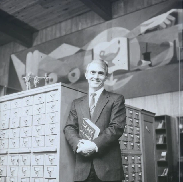 man in suit and tie next to large filing cabinet