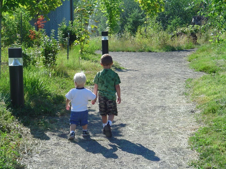 two small boys holding hands while walking