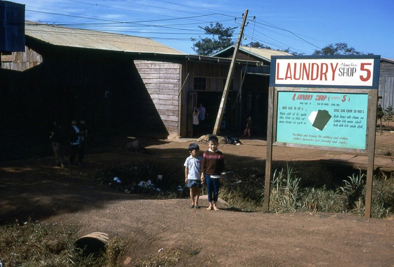 two boys standing outside a building in front of a sign
