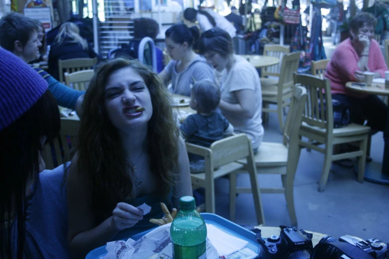 a girl sitting at a table in front of a camera