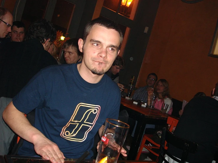 man sitting at a table in front of a fire in the middle of his glass