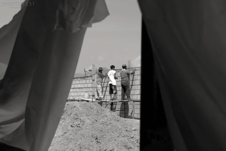 several people standing around a fence in the dirt