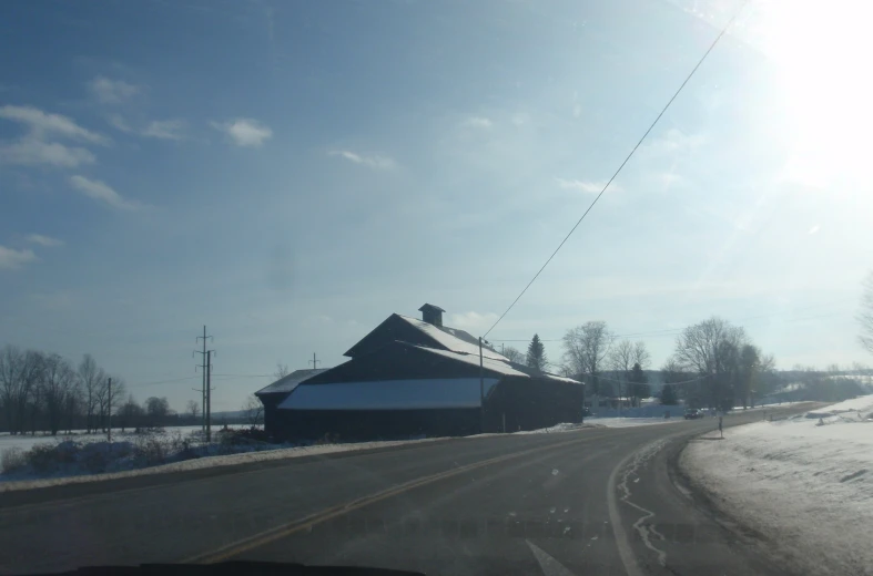 a snow covered road near a large barn