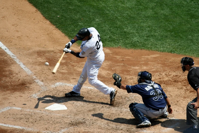the baseball player swings at the ball as he stands near home plate