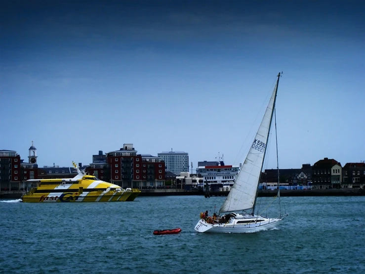 a sailboat is in a body of water near a city