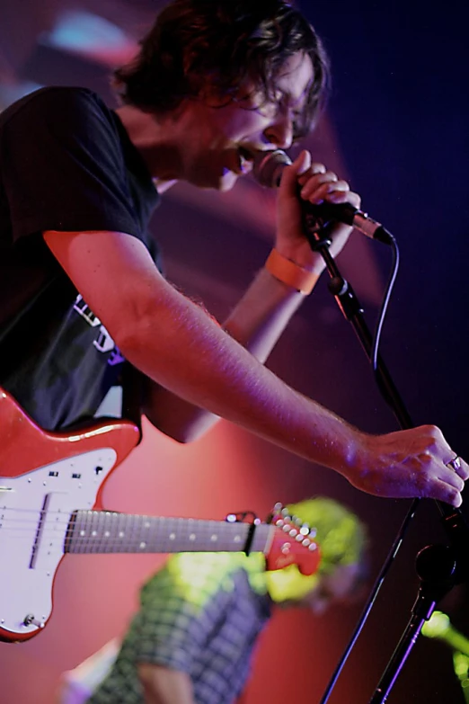 the person is singing into the microphone with a red guitar