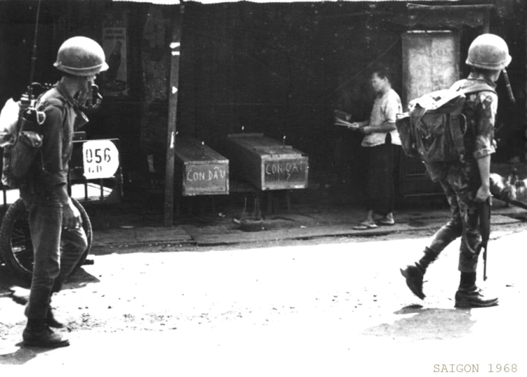 black and white po of soldiers walking in front of shack