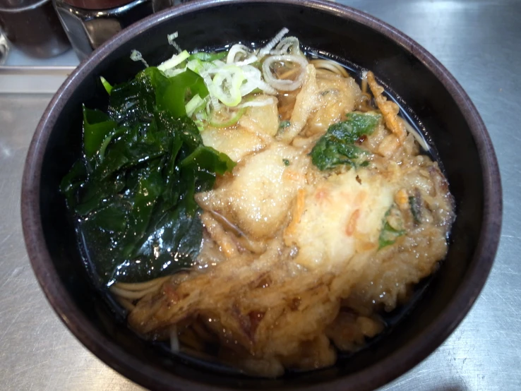 a bowl of food with noodles, vegetables, and greens