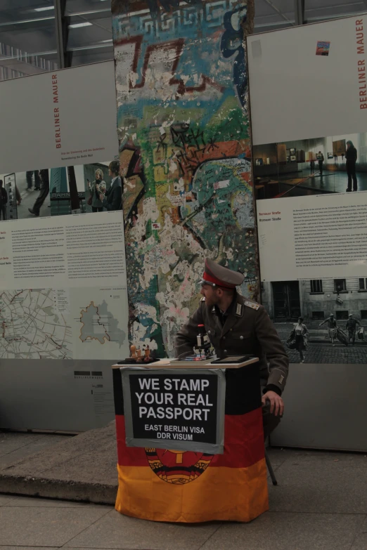 an older man sitting at a podium near posters