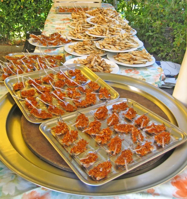 a table topped with plates and trays filled with food