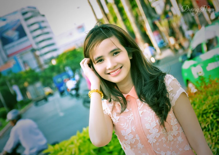 a young lady smiling while holding her hands to her head