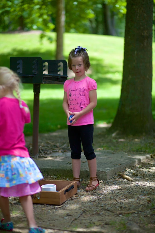 two little girls stand at a number 22 box in the park