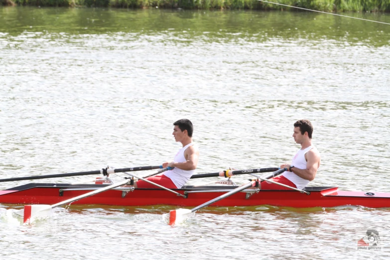 two rowers in red rowing boats on lake
