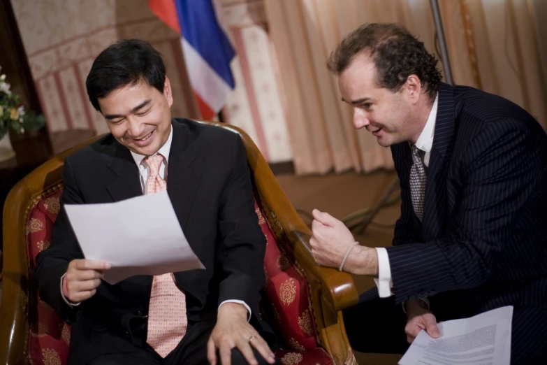 a couple of men sitting on chairs next to each other