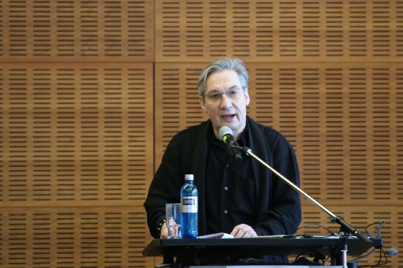 an older man at a podium speaking with a microphone