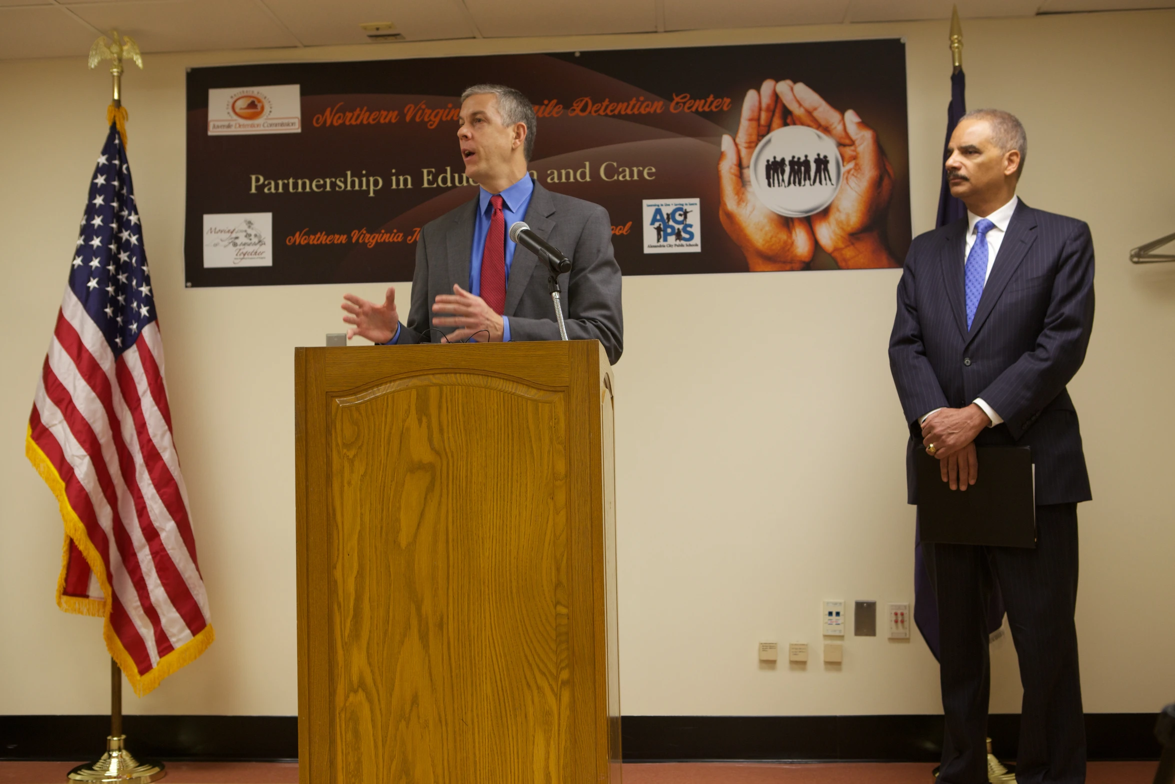 there are two men speaking at a podium