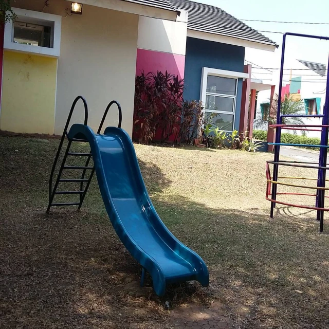 a blue slide in front of a colorful home