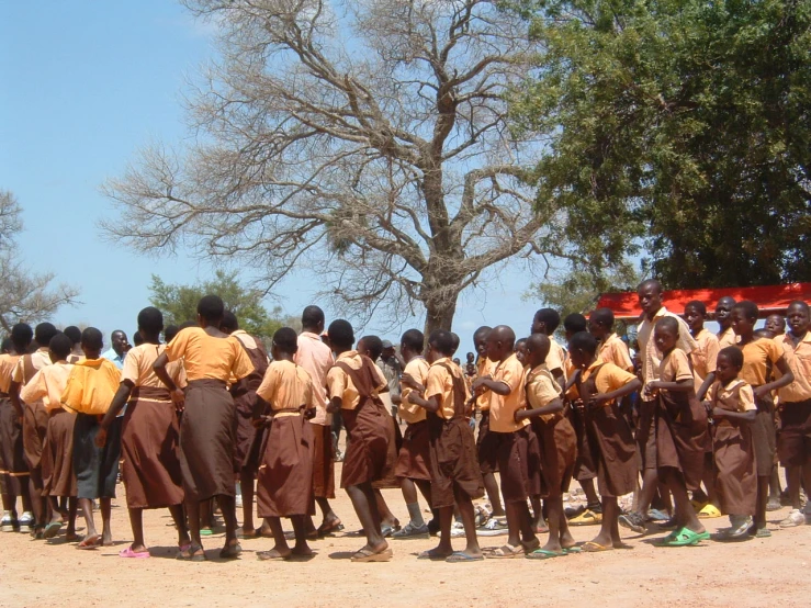 group of young men in uniforms walking on dirt