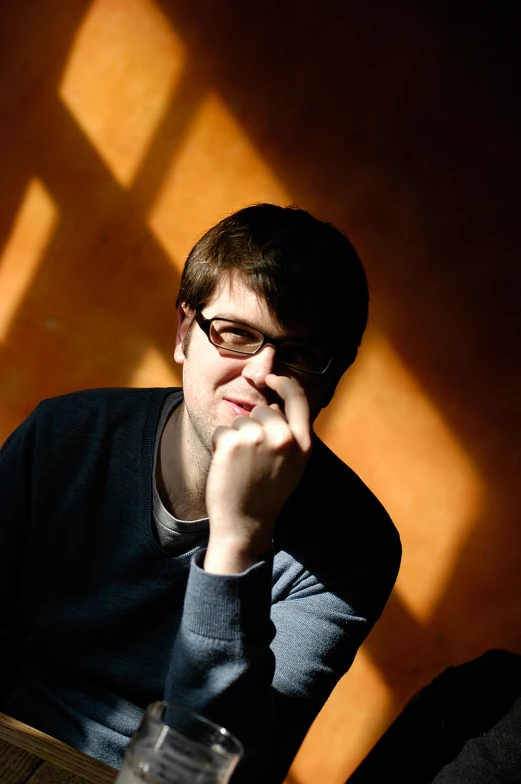 the young man is sitting and thinking at a desk