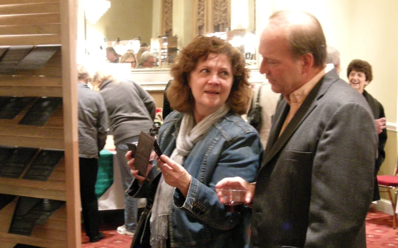 an older couple in a crowded restaurant looking at their cell phones