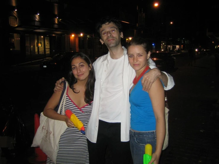 two women and a man standing outside at night