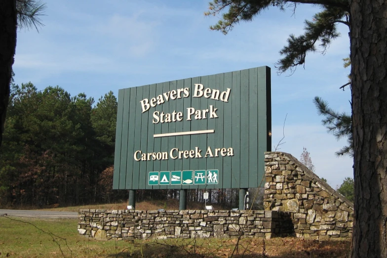 a large sign is near the entrance to a forest