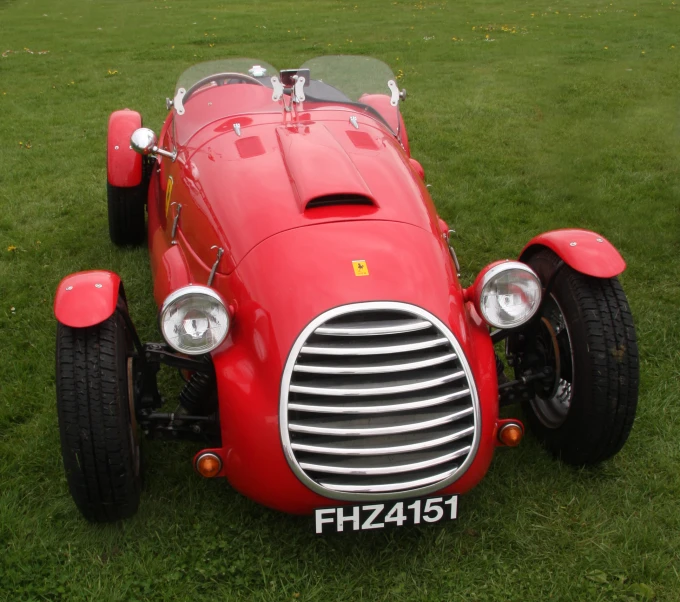 a red car is parked on some grass