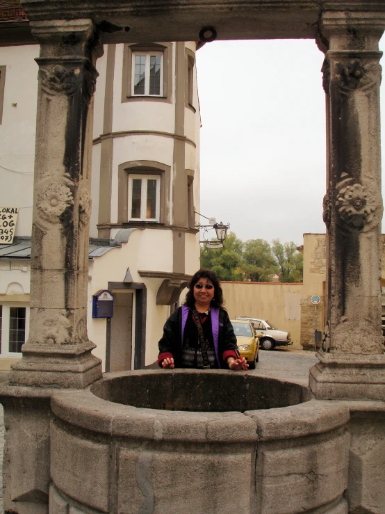 a woman standing in front of an ancient water fountain