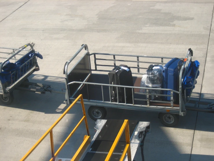 the luggage cart is carrying suitcases behind a railing